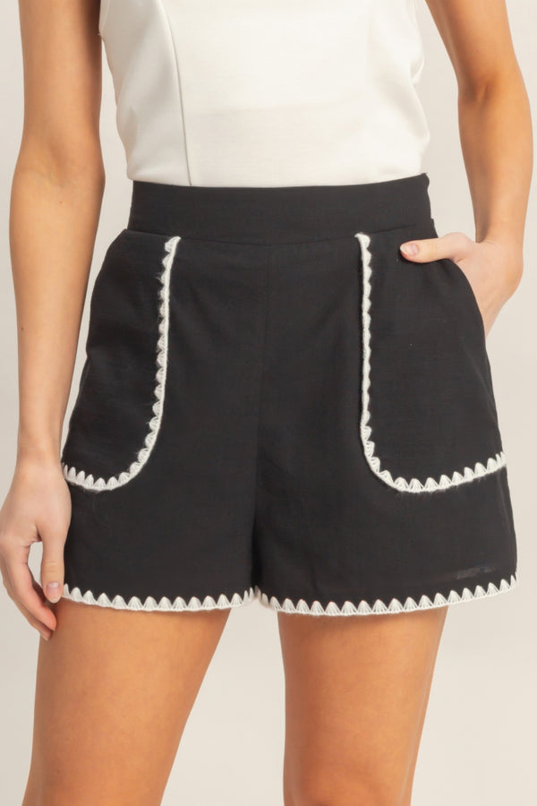 High-waisted black shorts with white scalloped trim and patch-style front pockets