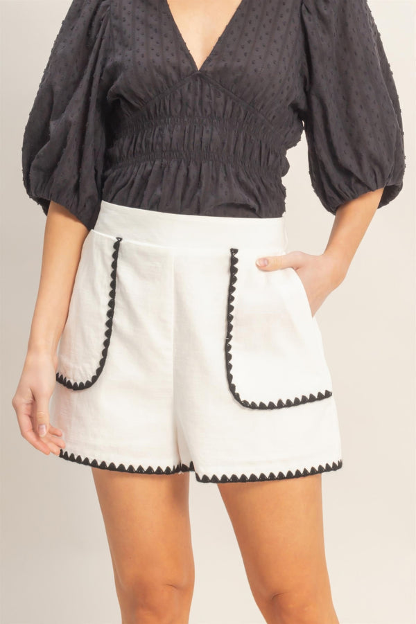 White high-waisted shorts with scallop trim pockets and black edging